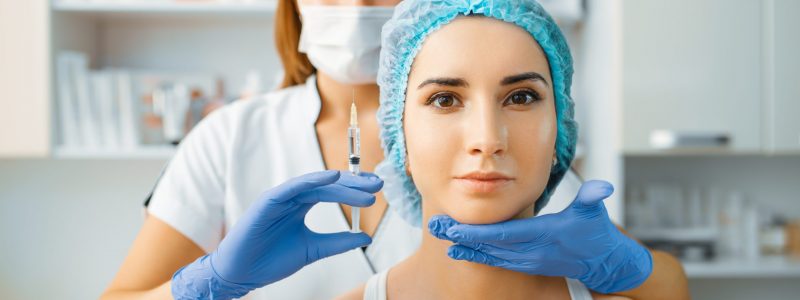 Cosmetician holds syringe with injection of botox at female patient face. Rejuvenation procedure in beautician salon. Doctor and woman, cosmetic surgery against wrinkles and aging